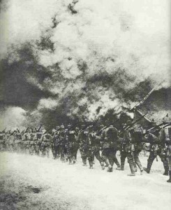 Deutsche Infanterie marschiert durch brennendes Dorf