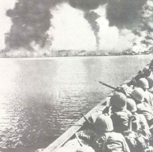 Japanische Soldaten betrachten von ihren Landungsfahrzeugen aus das brennende Manila. 