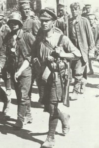 Soldat mit Hemdsärmeln, Shorts, Mütze und Wickelgamaschen