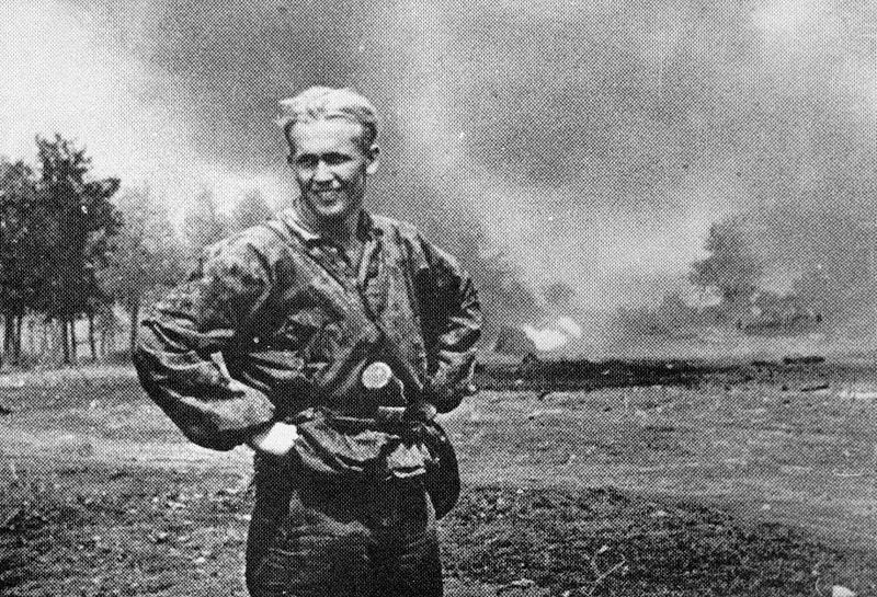 SS-Soldat posiert vor niedergebrannten Haus